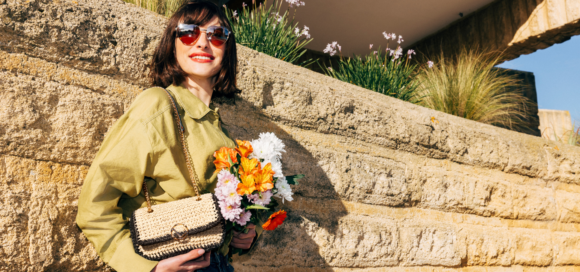 Jeune femme avec un sac porté épaule LOLLIPOPS et un bouquet de fleurs